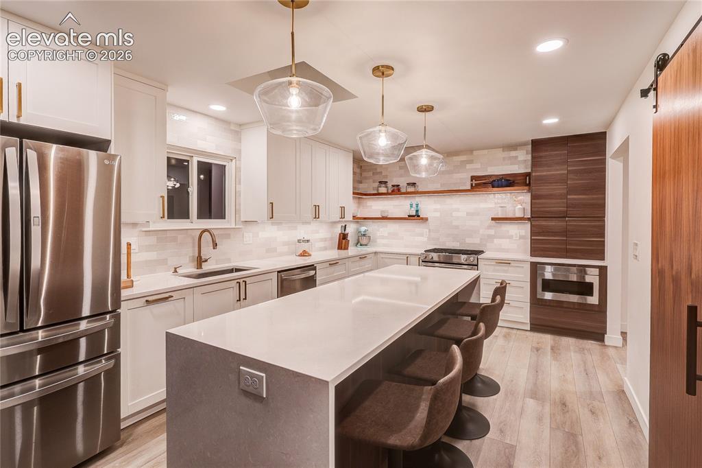 Image 13 of 50: Contemporary kitchen featuring a large center island, white cabinetry, inte