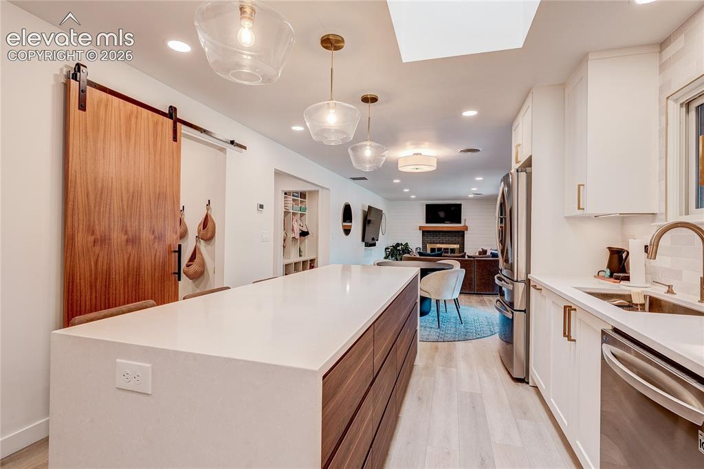 Image 14 of 50: Kitchen island with waterfall countertop, stainless steel appliances, white