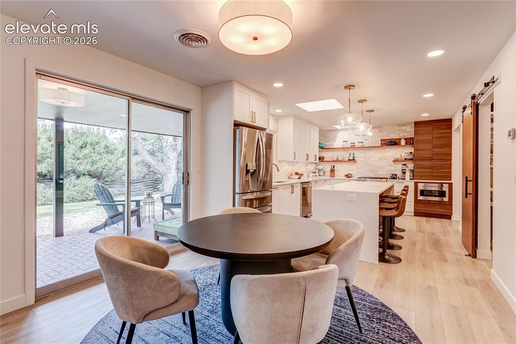 Image 16 of 50: Kitchen with light wood-finish flooring, white cabinetry, a large center is