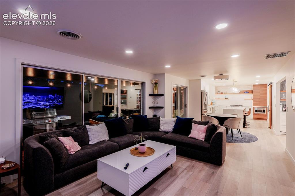 Image 18 of 50: Recessed ceiling lighting, wood-finish flooring, sliding glass doors, built