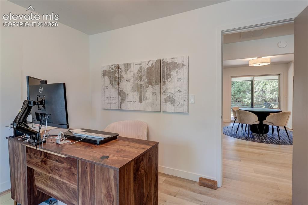 Image 26 of 50: Wood-finish flooring throughout, light-toned walls, and an open doorway lea