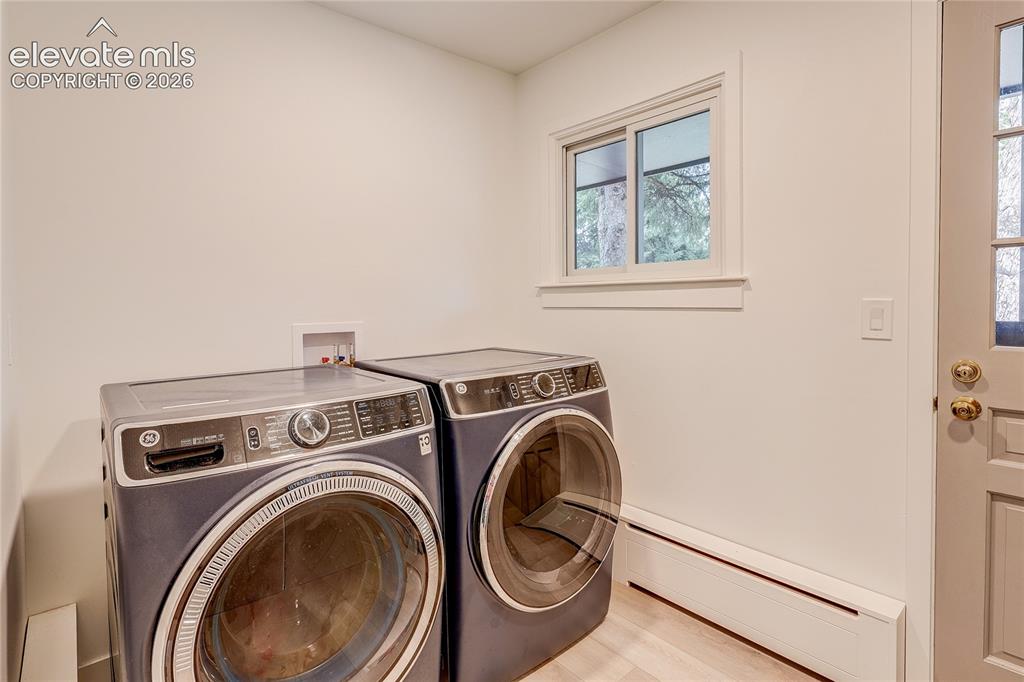 Image 28 of 50: Laundry area with a light wood-finish floor and a white framed window