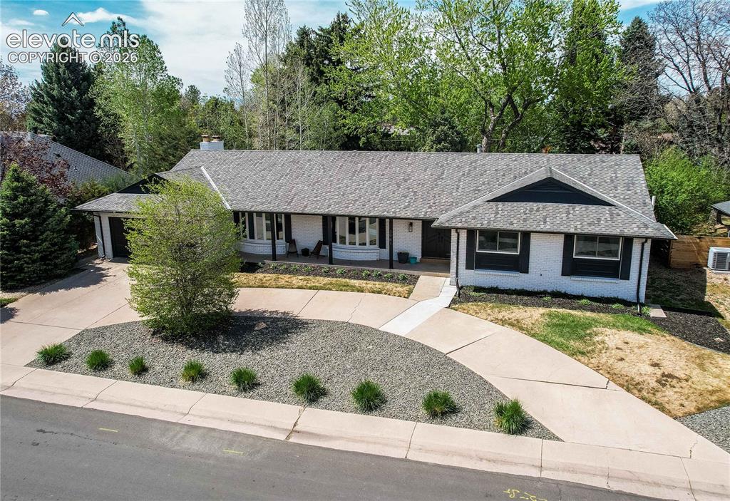 Image 3 of 50: Ranch-style exterior with a gray shingle roof, white brick facade, and dark