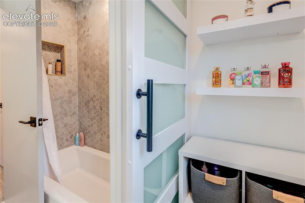 Image 31 of 50: Sliding barn door with frosted panels, white floating shelves, built-in she