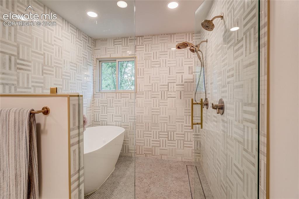 Image 38 of 50: Floor-to-ceiling geometric-patterned wall tile, walk-in shower with glass e