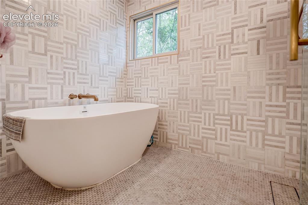 Image 39 of 50: Freestanding soaking tub with wall-mounted bronze-finish faucet, surrounded