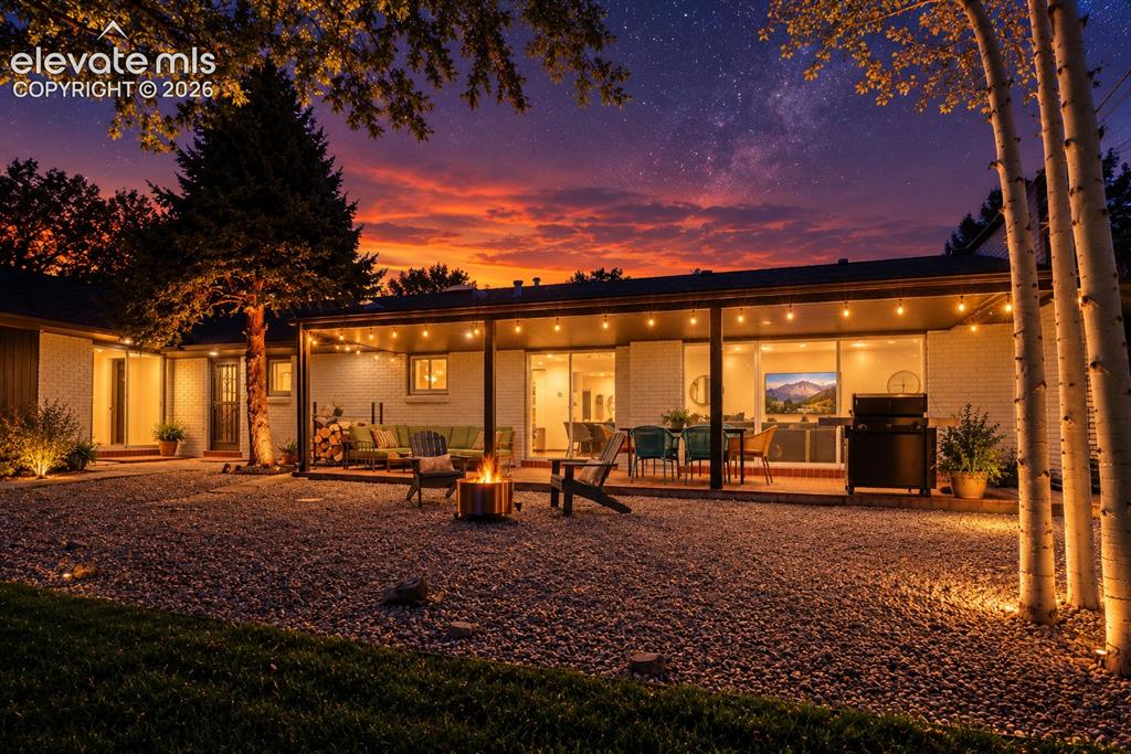 Image 43 of 50: Extensive gravel yard with perimeter landscaping, covered patio featuring s