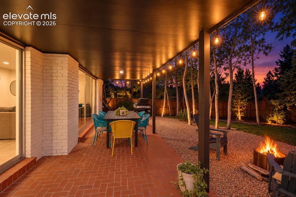 Image 44 of 50: Covered patio featuring a brick paver surface, string lighting, and ample s