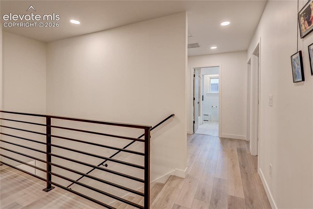 Image 47 of 50: Recessed lighting, wood-finish flooring, and black metal railing