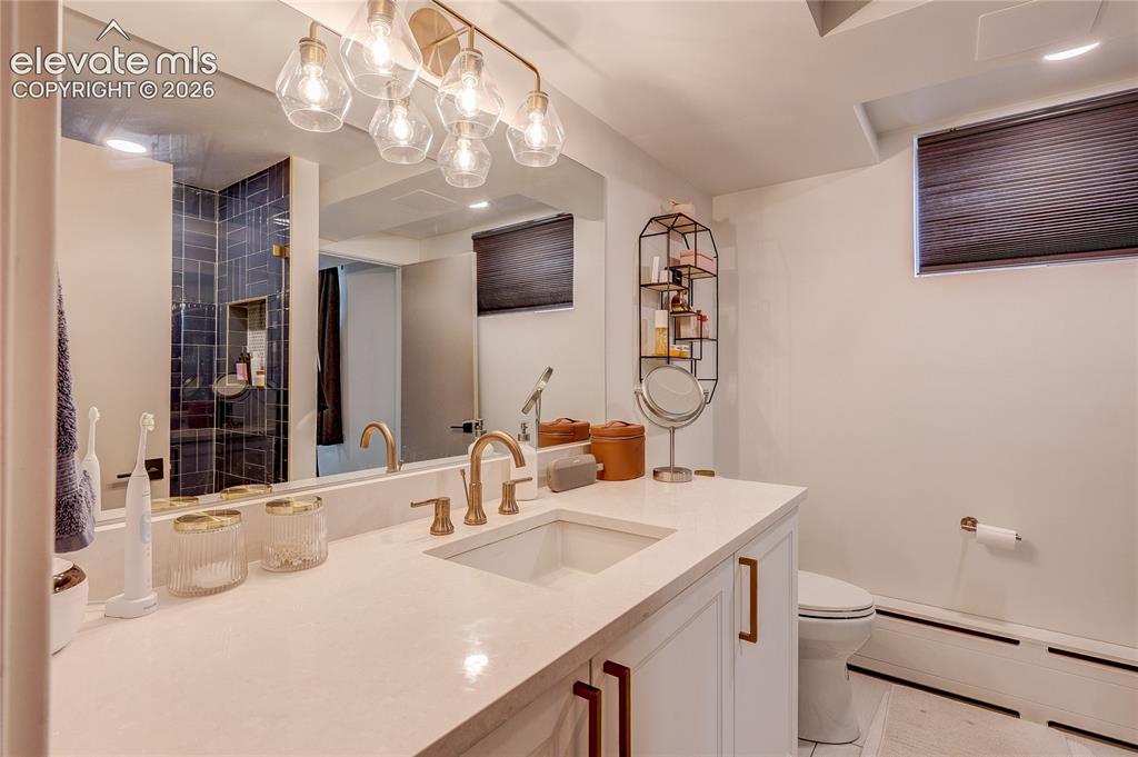 Image 48 of 50: White vanity with integrated sink, gold-tone fixtures, and a large mirror