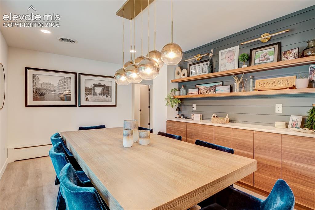 Image 6 of 50: Gold-finish linear chandelier with glass globes, wood-finish flooring, rece