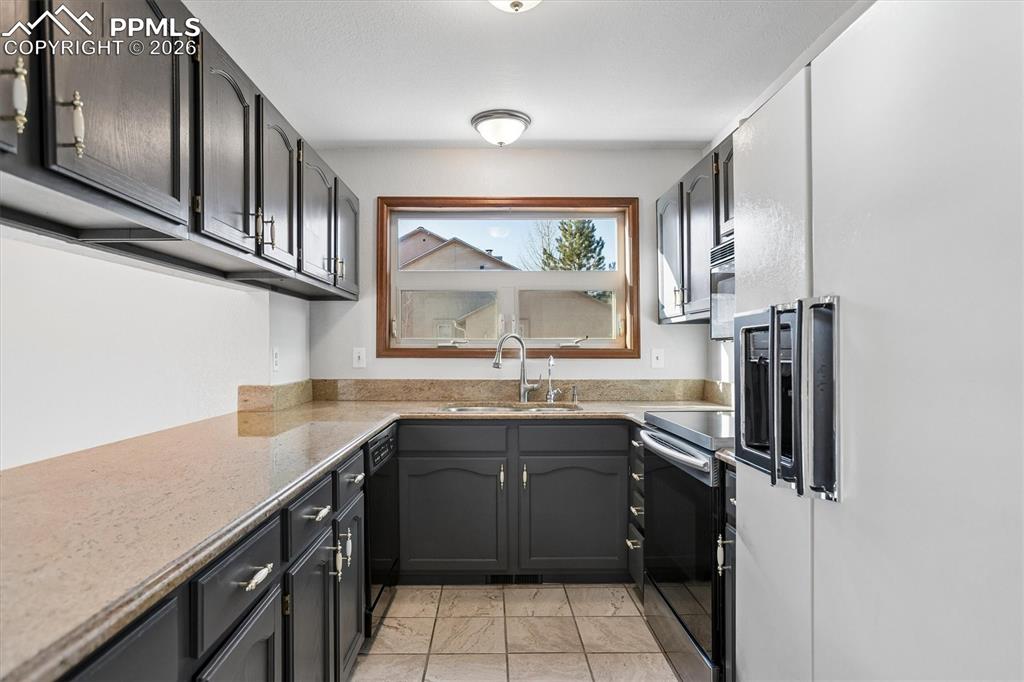 Image 10 of 29: Kitchen with white fridge with ice dispenser, range with electric stovetop,