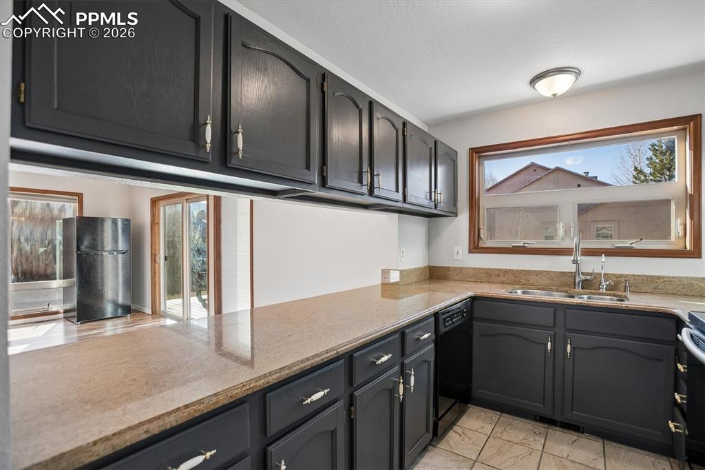 Image 11 of 29: Kitchen with light stone countertops and black appliances