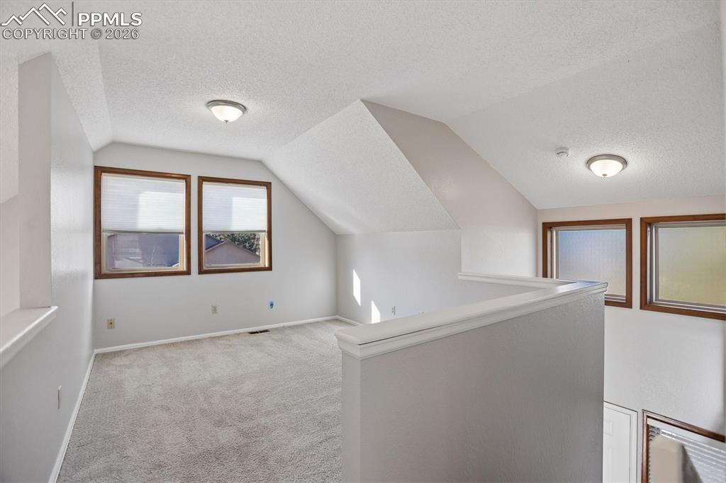 Image 13 of 29: Additional living space featuring a textured ceiling and light carpet
