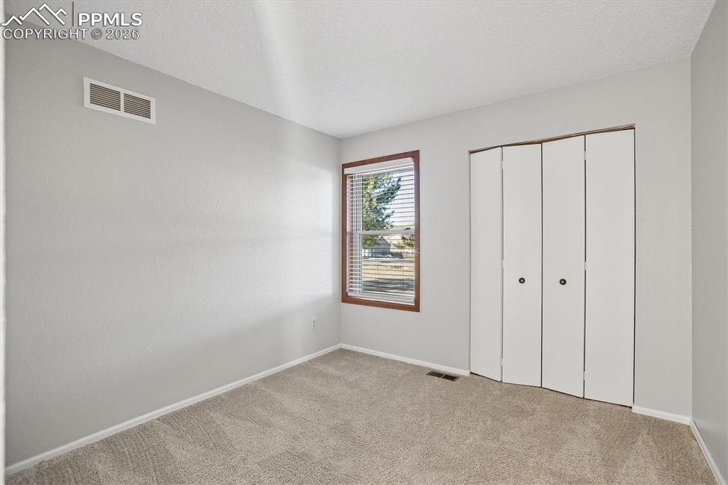 Image 21 of 29: Unfurnished bedroom with light colored carpet, a closet, and a textured cei