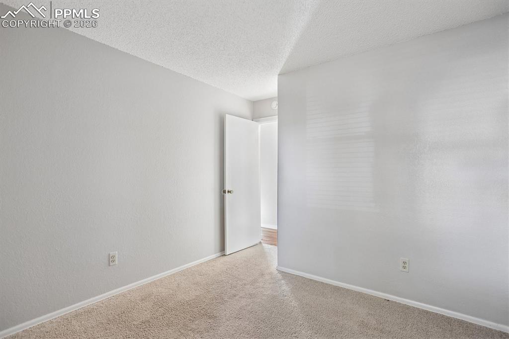 Image 22 of 29: Carpeted empty room with baseboards and a textured ceiling