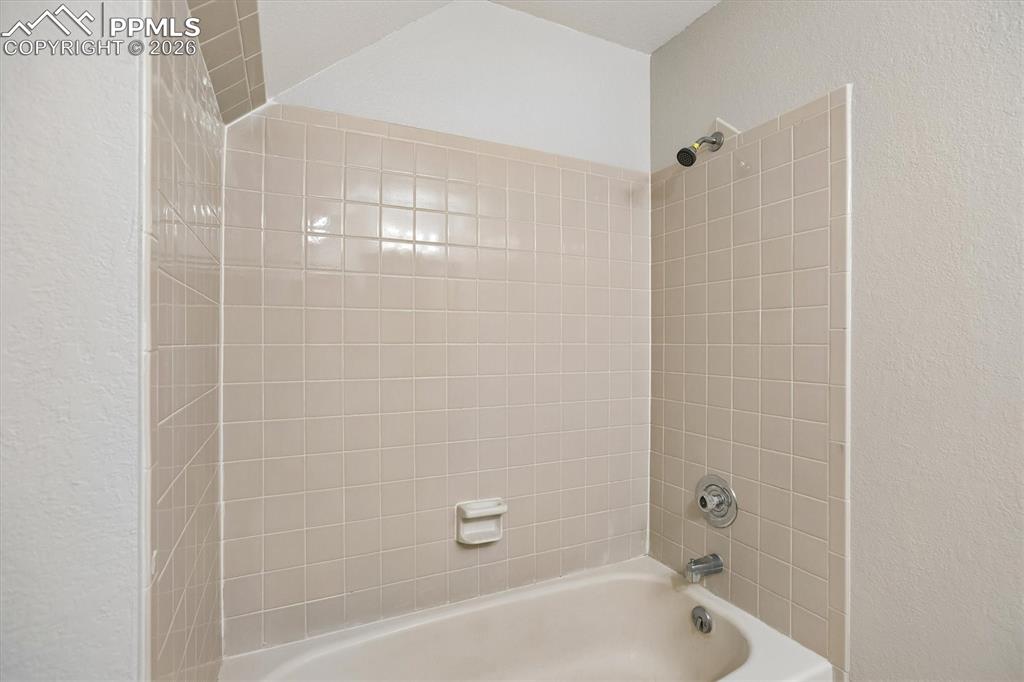 Image 24 of 29: Full bathroom featuring a textured wall and shower / tub combination