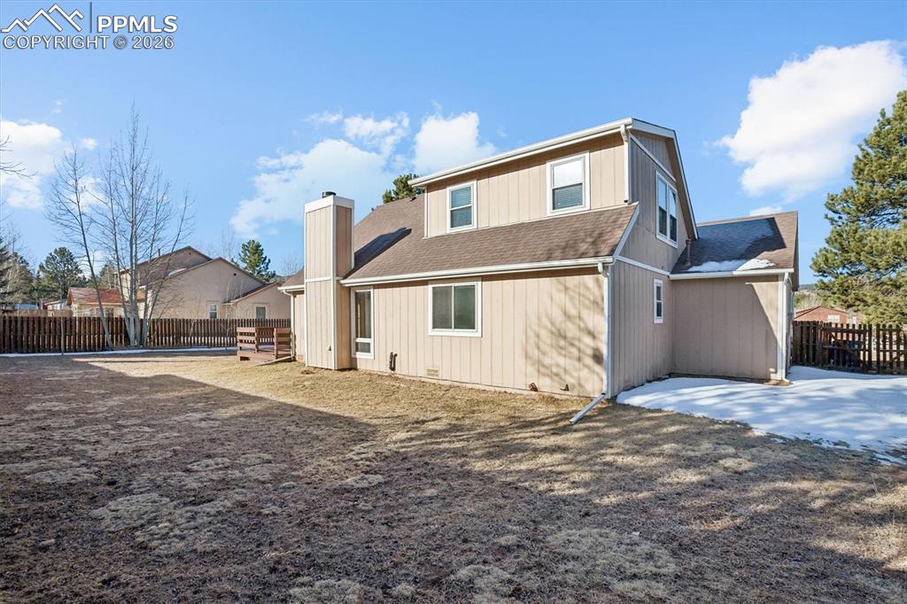 Image 29 of 29: Rear view of house with a fenced backyard, a shingled roof, and a chimney