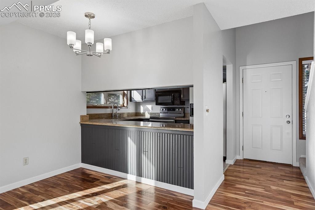 Image 3 of 29: Kitchen featuring dark wood-style flooring, electric range, dark stone coun