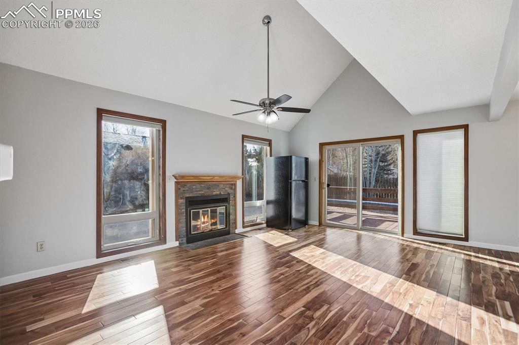 Image 5 of 29: Unfurnished living room featuring vaulted ceiling, dark wood-style flooring
