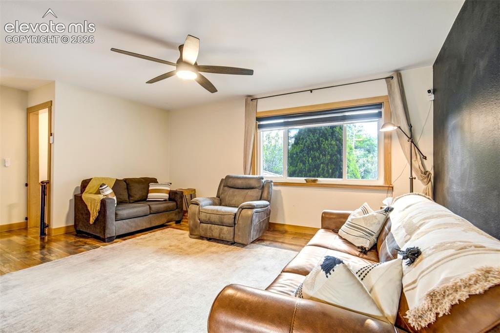 Image 11 of 50: Spacious living area featuring wood-finish flooring, a large window with na