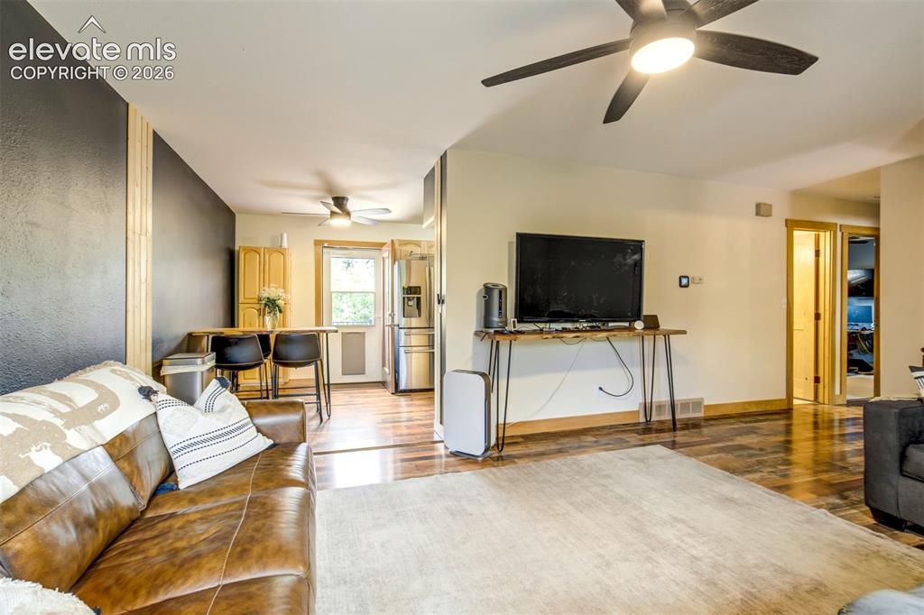 Image 12 of 50: Living area featuring wood-finish flooring, a contemporary ceiling fan with