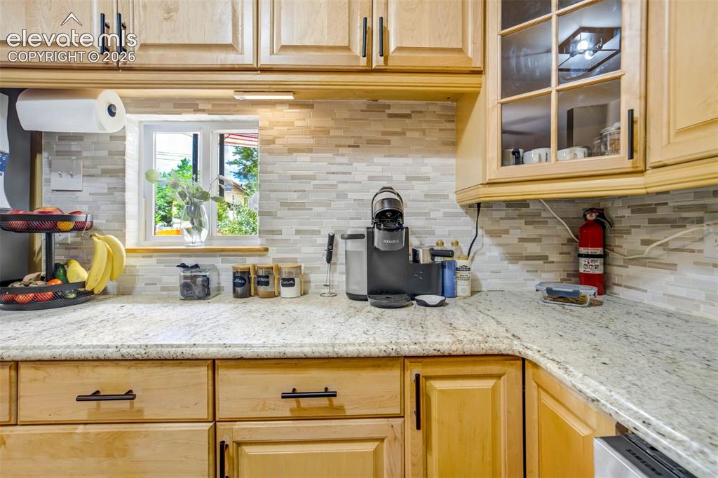 Image 16 of 50: Light wood cabinetry with black hardware, granite-style countertops, and a 