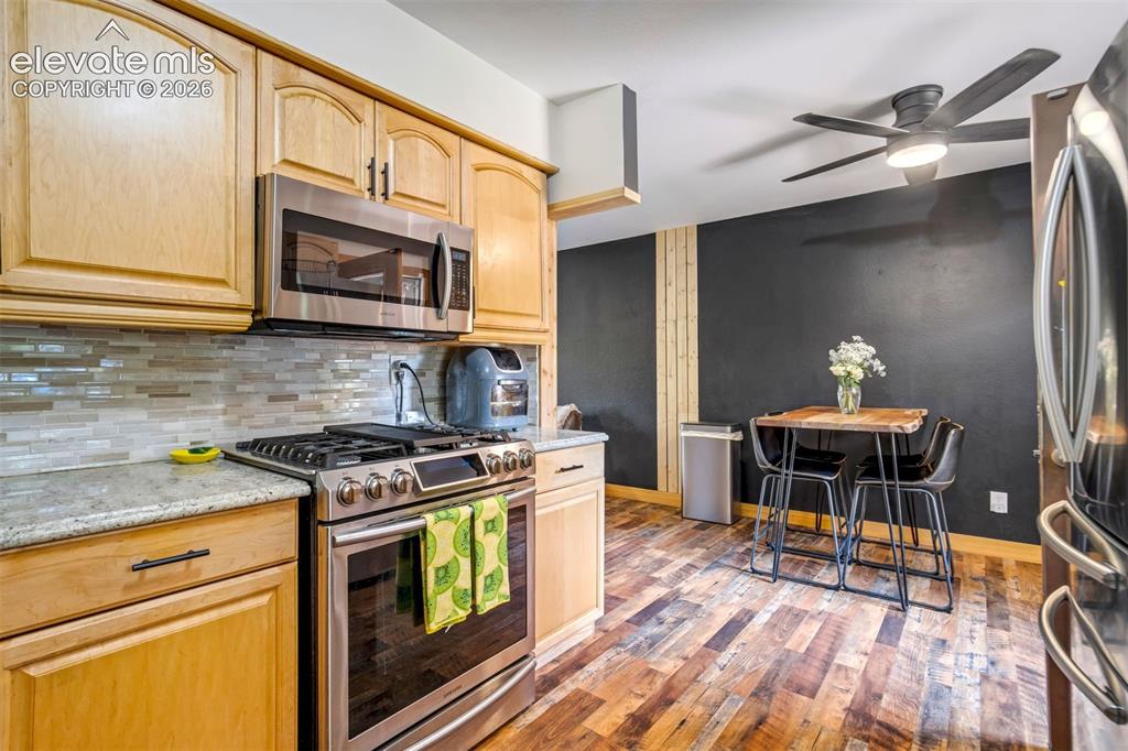 Image 17 of 50: Kitchen featuring wood-finish flooring, light wood cabinetry, stainless ste