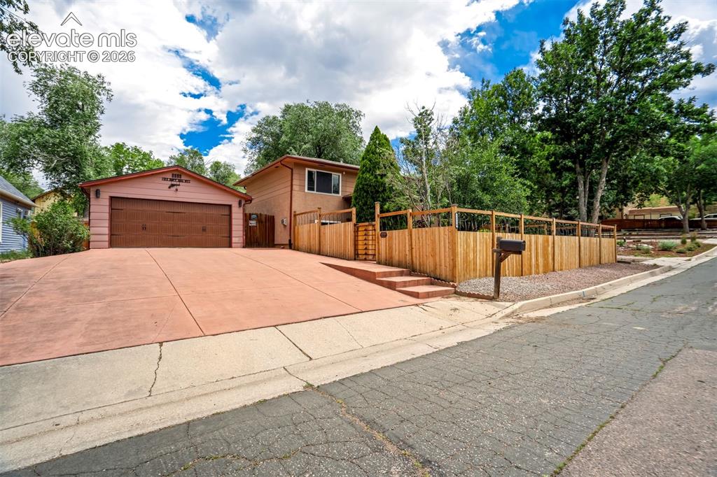 Image 2 of 50: Stucco exterior featuring a two-car garage with a brown door, a stained con