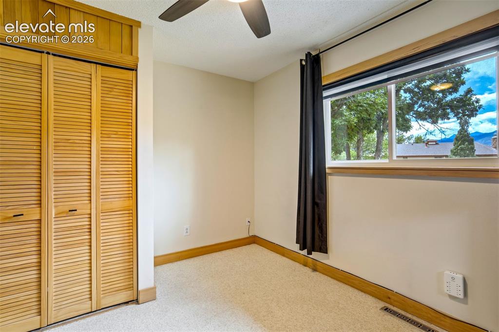 Image 23 of 50: Carpeted room with a ceiling fan, a window with a wood-finish sill, and lou