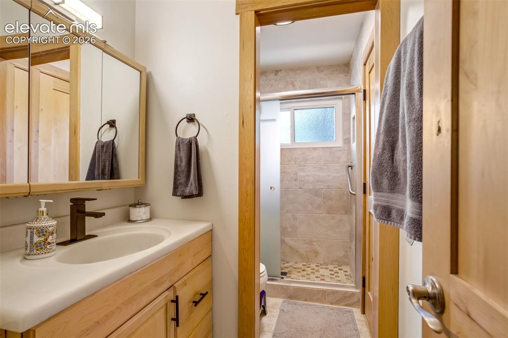 Image 24 of 50: Bathroom featuring a light wood-finish vanity with an integrated sink and b