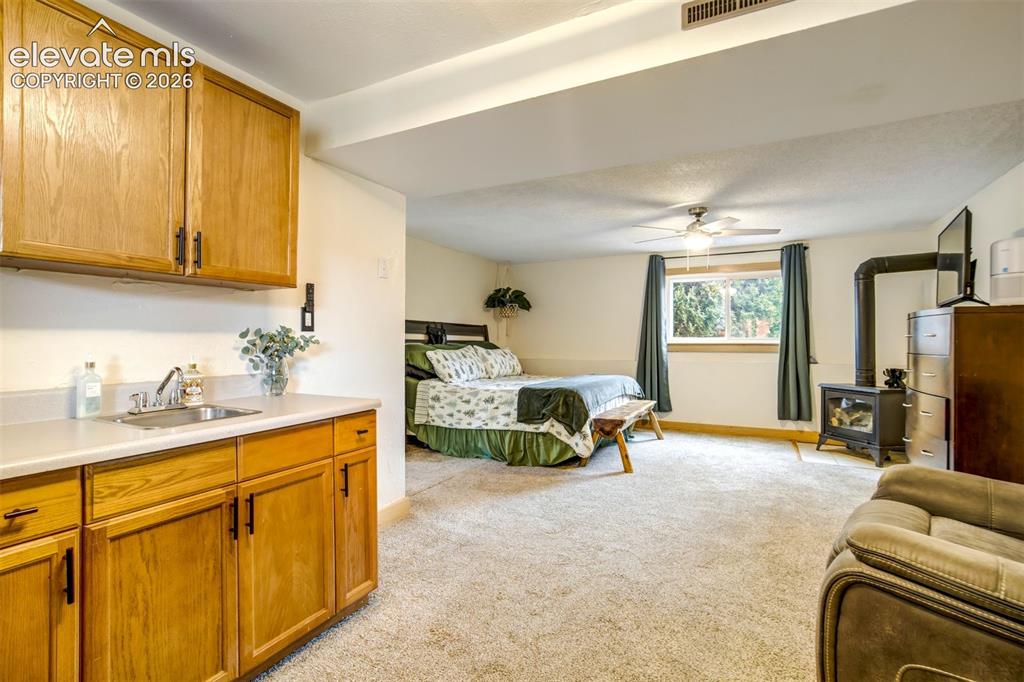 Image 28 of 50: Integrated living space featuring a built-in wet bar with wood cabinetry an