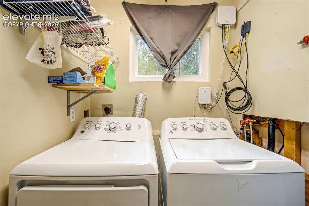 Image 33 of 50: Dedicated laundry area featuring a window, built-in shelving, and a wood-fi