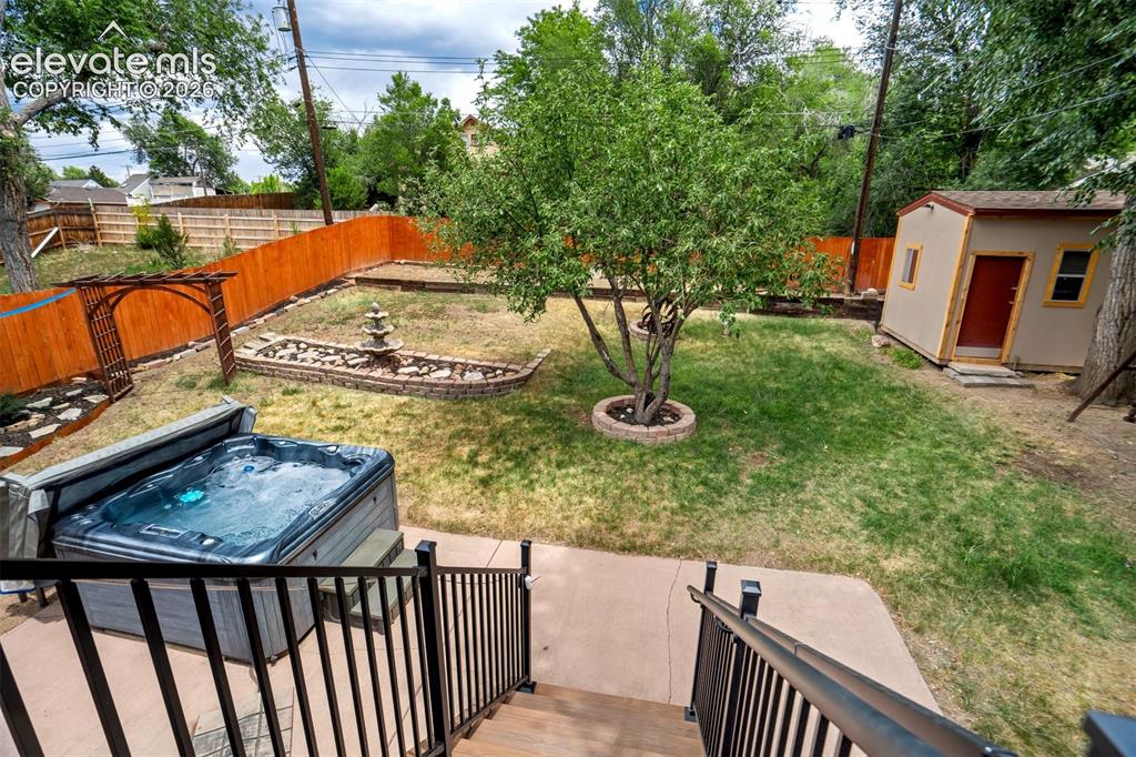 Image 35 of 50: Expansive backyard featuring a hot tub, fenced perimeter, mature tree, deco