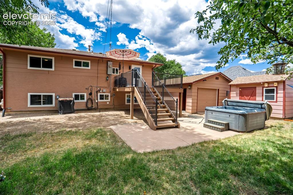 Image 36 of 50: Expansive backyard featuring a concrete patio, a built-in spa, a detached g