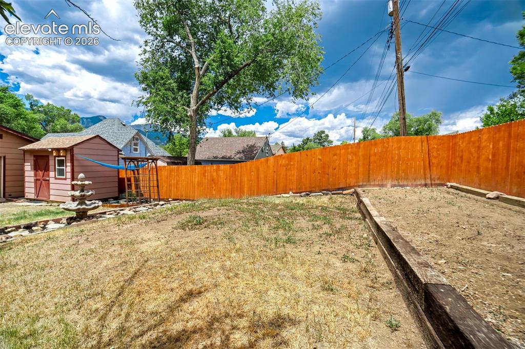 Image 39 of 50: Expansive yard space featuring a privacy fence, an integrated garden bed, a