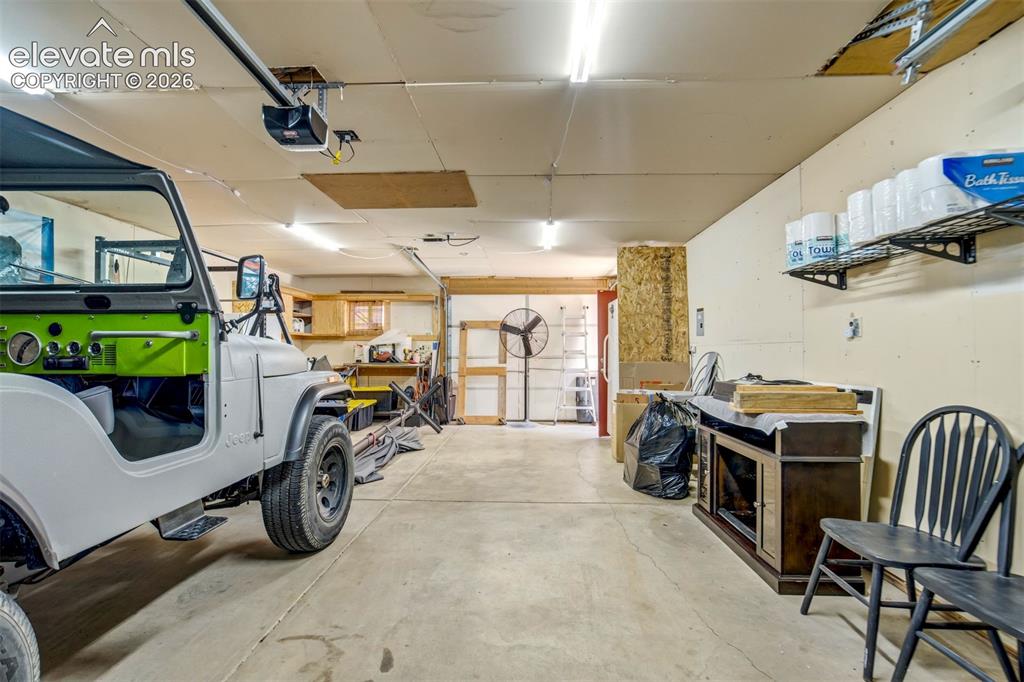 Image 43 of 50: Spacious garage featuring a concrete floor, overhead lighting, garage door 