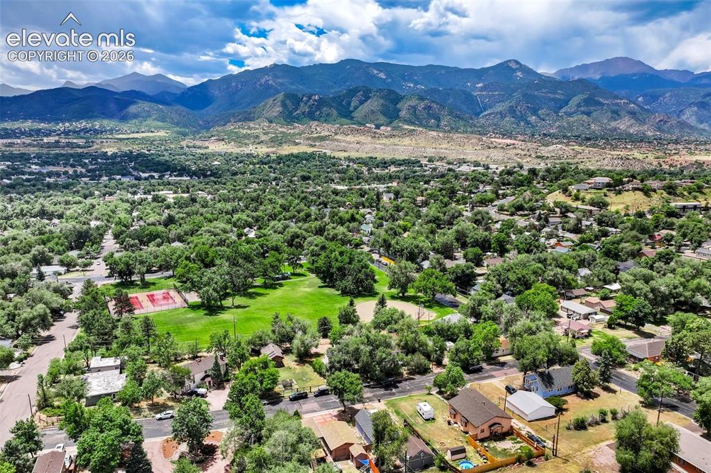 Image 46 of 50: Expansive landscape featuring an open green space, mature trees, and mounta