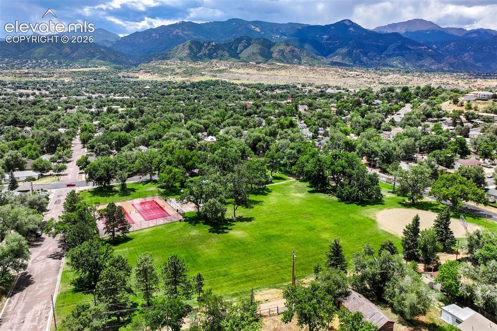 Image 48 of 50: Expansive green space featuring a tennis court and baseball diamond, surrou