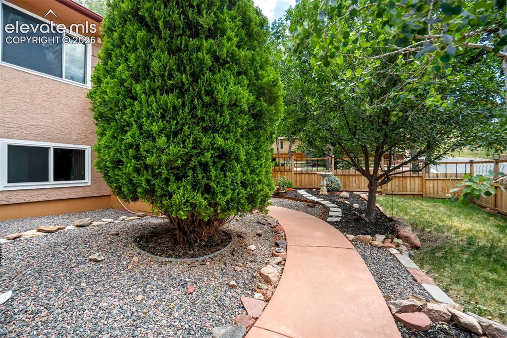 Image 6 of 50: Curved concrete pathway bordered by natural stone and gravel, leading throu