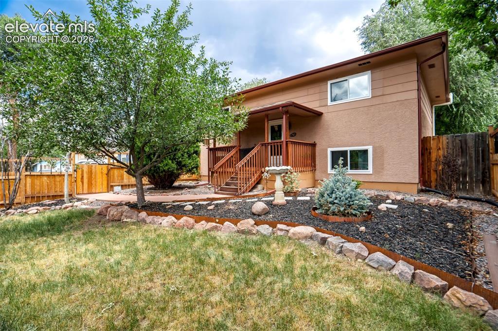Image 7 of 50: Split-level residence featuring a wood deck and staircase leading to an ent