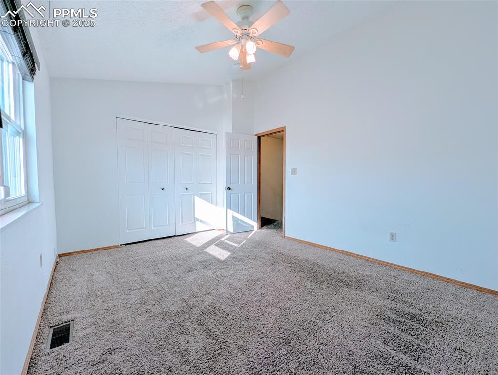 Image 7 of 19: Unfurnished bedroom with lofted ceiling, carpet, a closet, and a ceiling fa