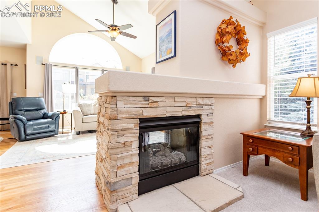 Image 11 of 47: Living room with a ceiling fan, a fireplace, plenty of natural light, vault