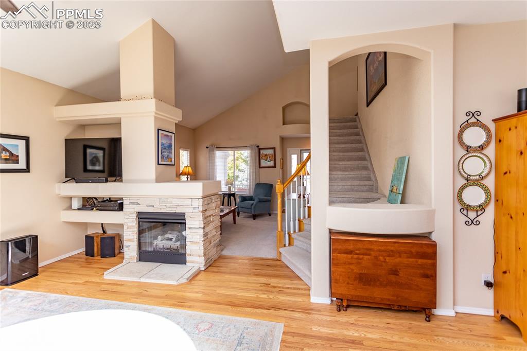 Image 12 of 47: Living area featuring stairs, light wood finished floors, vaulted ceiling,