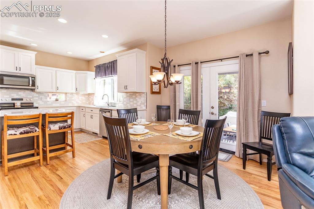 Image 18 of 47: Dining room with a chandelier, light wood finished floors, and recessed lig