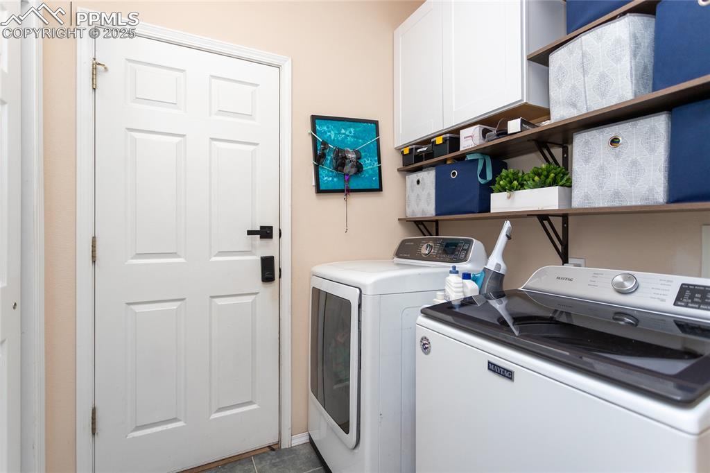 Image 22 of 47: Laundry room with cabinet space, separate washer and dryer, and dark tile p