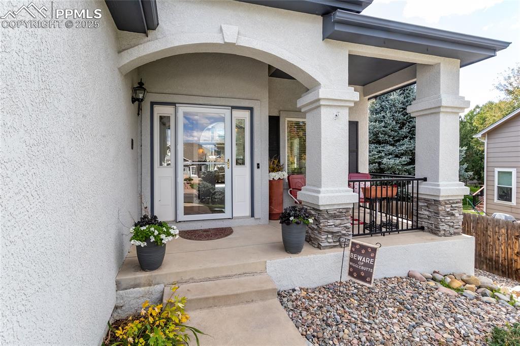 Image 4 of 47: Doorway to property featuring stucco siding and a porch
