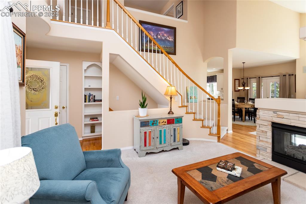 Image 6 of 47: Living room with stairway, built in features, a towering ceiling, wood fini