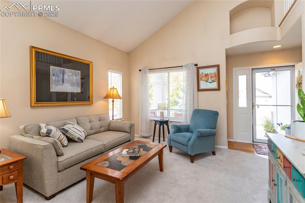 Image 7 of 47: Living room with light colored carpet and high vaulted ceiling