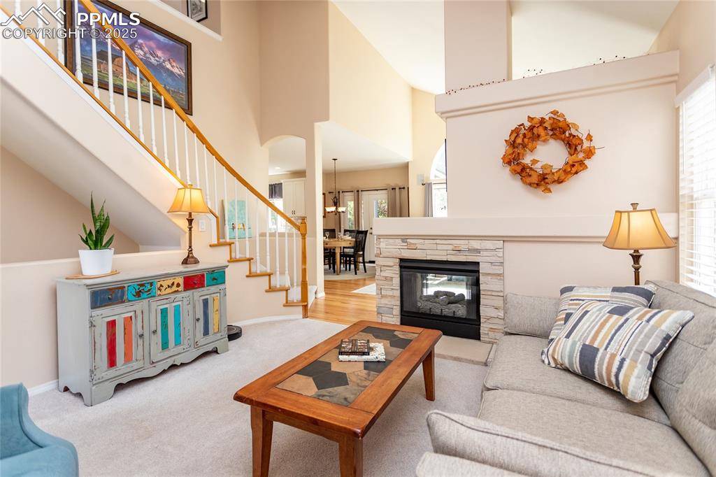 Image 8 of 47: Carpeted living room with stairs, arched walkways, a high ceiling, and a st